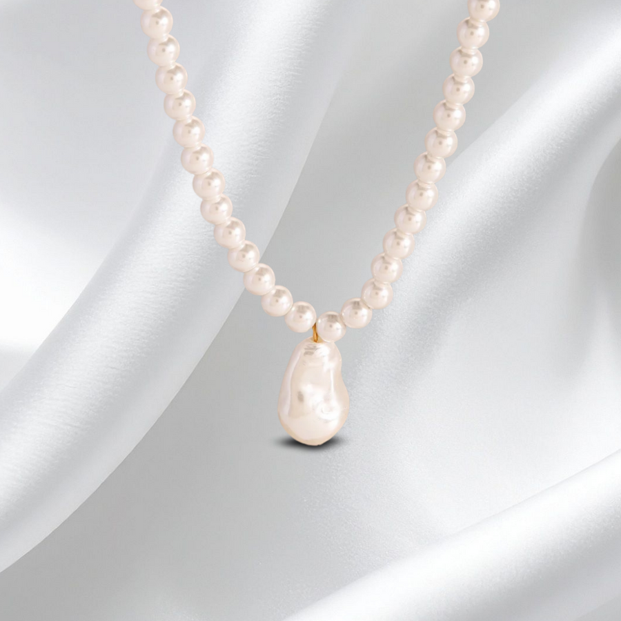 Pearl necklace with a teardrop-shaped pearl pendant on a white fabric background