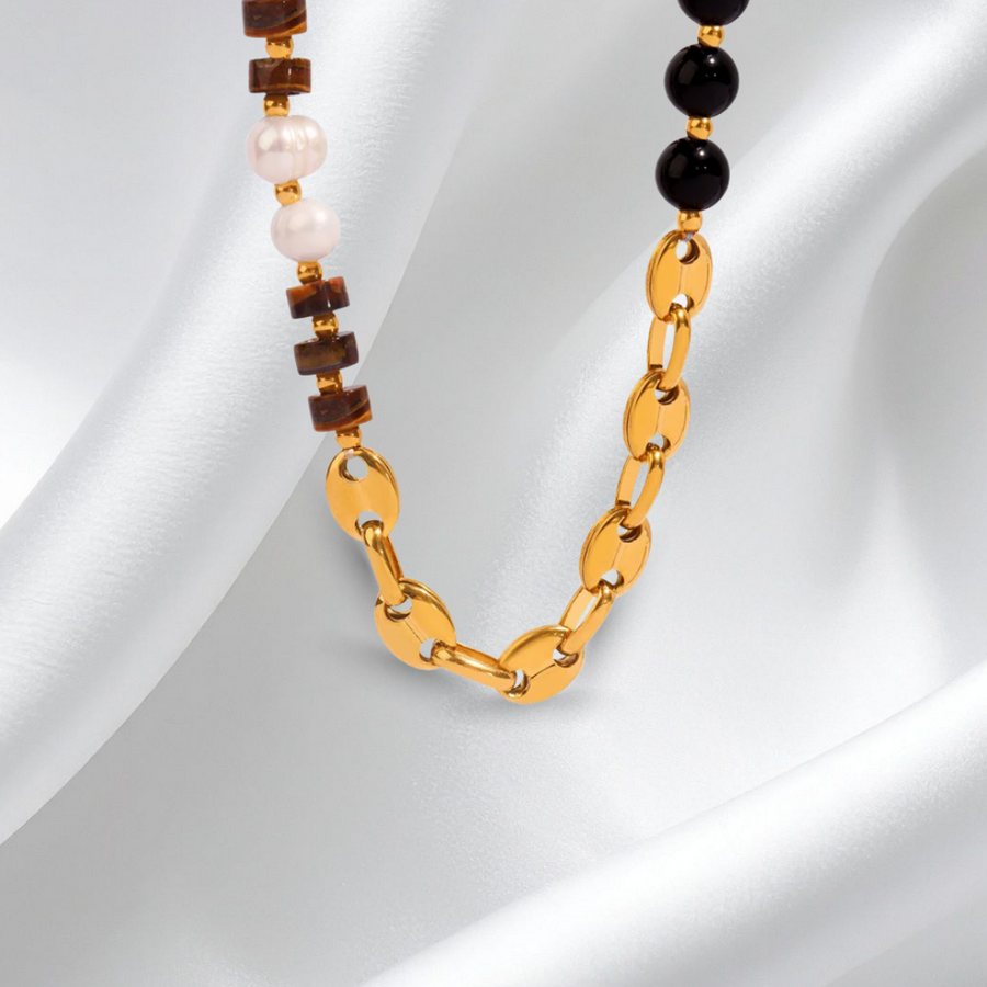 Necklace with gold chain and beads on a white fabric background