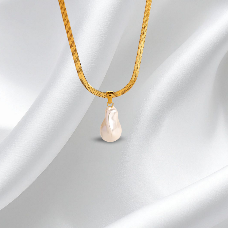 Gold necklace with a pearl pendant on a white fabric background