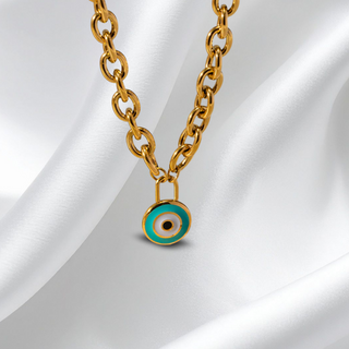 Gold chain necklace with a turquoise evil eye pendant on a white fabric background