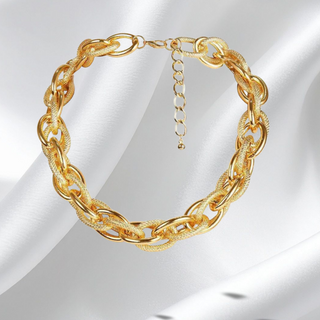 Gold chain necklace on a white satin background