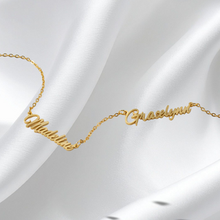 Gold personalized necklace with 'Madelaine' and 'Graceful' on a white satin background