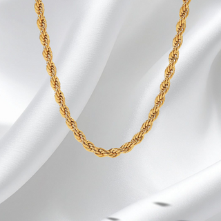 Gold rope chain necklace on a white fabric background