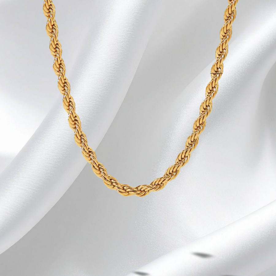 Gold rope chain necklace on a white fabric background