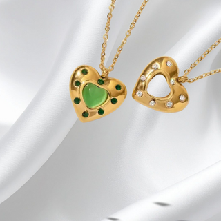 Two gold heart-shaped pendants on a white fabric background