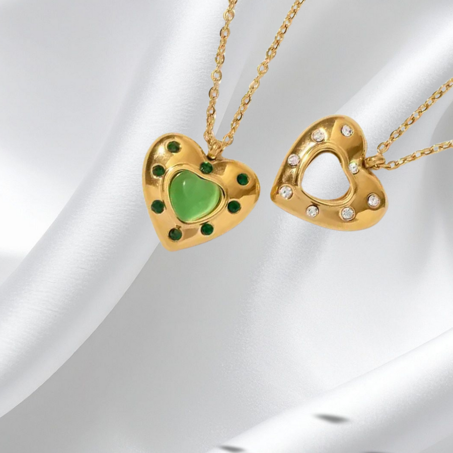 Two gold heart-shaped pendants on a white fabric background