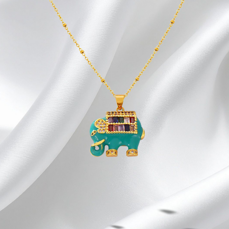 Gold and turquoise elephant pendant necklace on a white fabric background