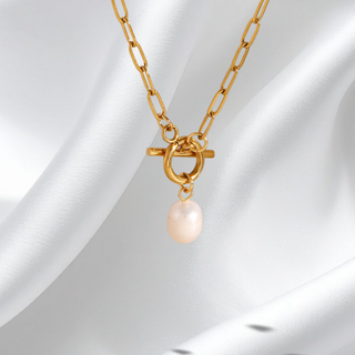 Gold necklace with a pearl pendant on a white fabric background