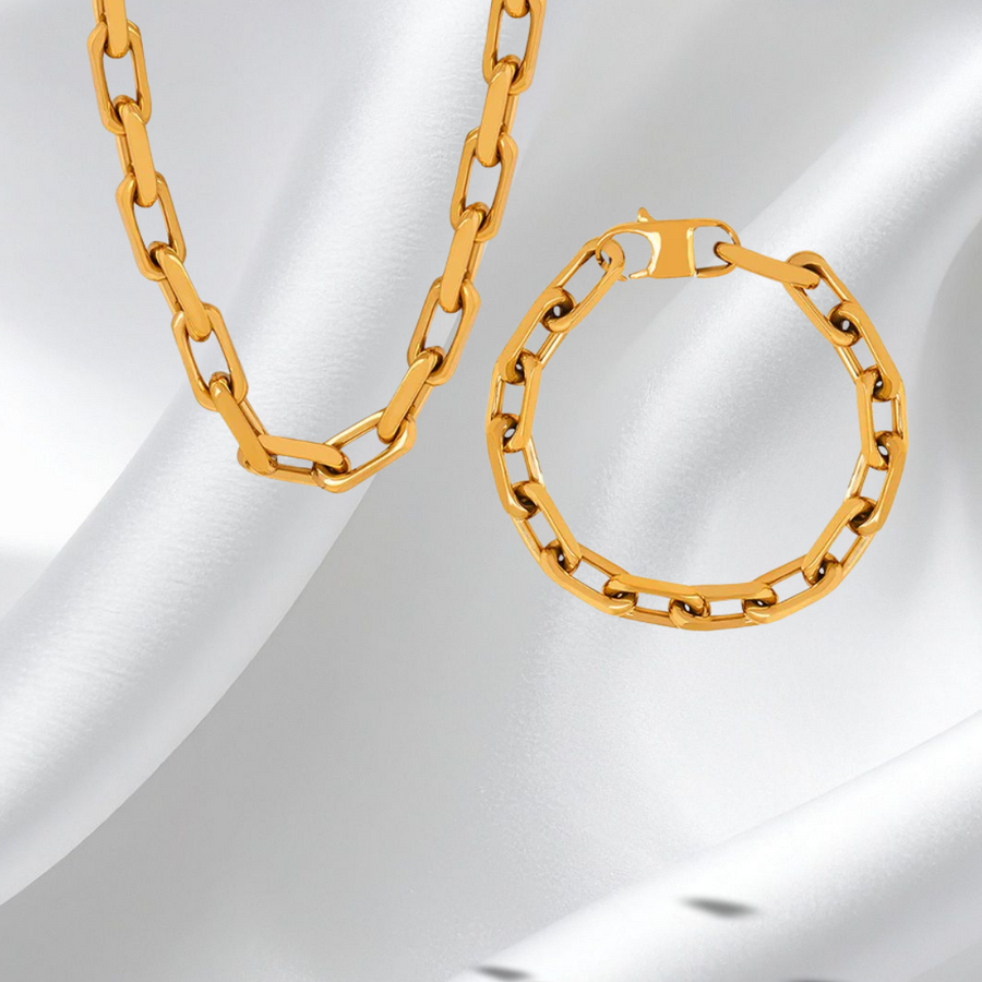 Gold chain necklace and hoop earring on a white fabric background