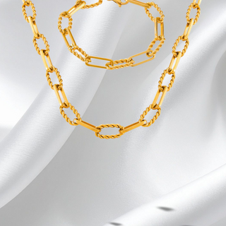 Gold chain necklace and bracelet on a white fabric background