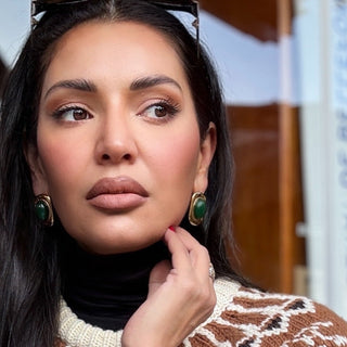 Woman wearing green earrings with a blurred background