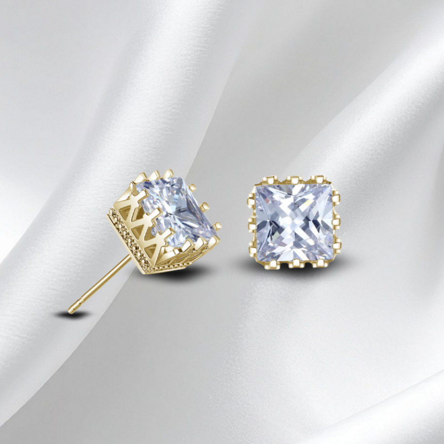 Gold  stud earrings with clear gemstones on a white fabric background
