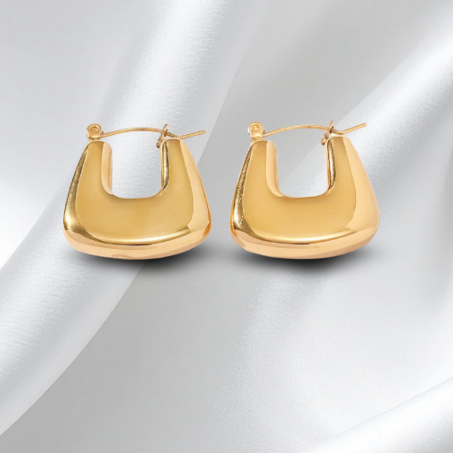 Gold hoop earrings on a white fabric background