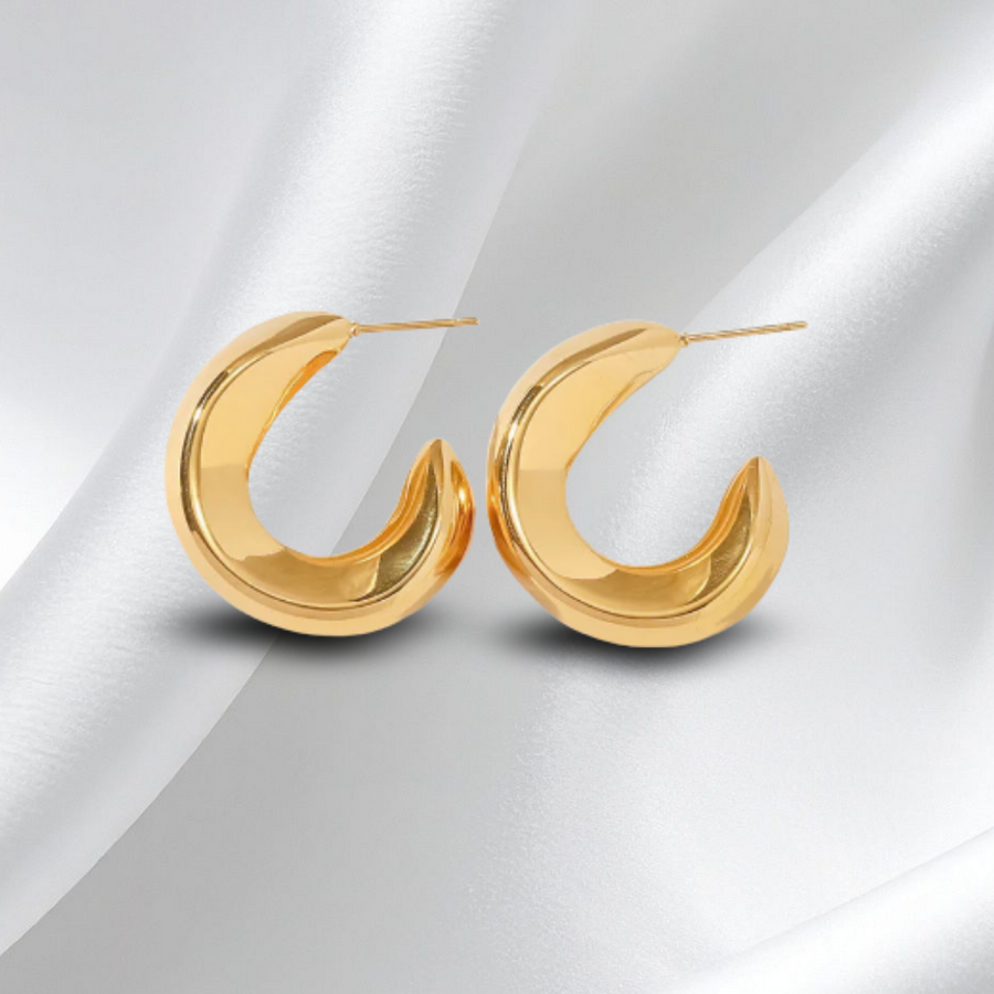 Pair of gold hoop earrings on a white fabric background