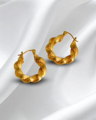 Pair of gold hoop earrings on a white fabric background