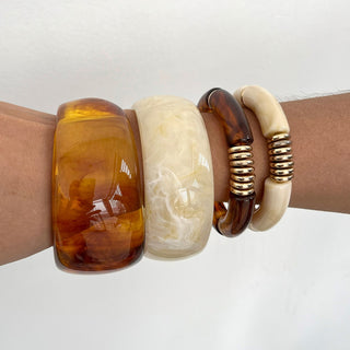 Four bracelets on a wrist against a white background
