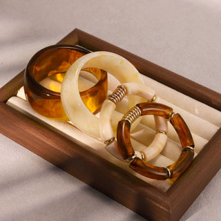 Set of three tortoiseshell bangles in a wooden box on a neutral background
