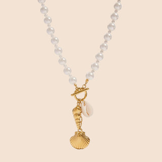 Pearl necklace with gold shell and moon charm on a white background