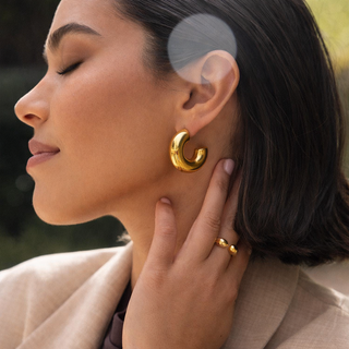 Woman wearing luna gold hoop earrings and ring.