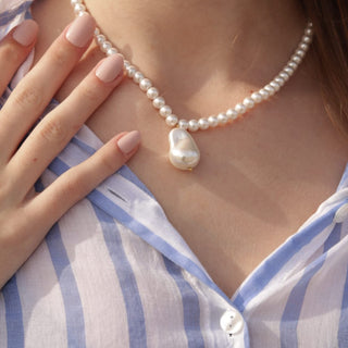 Pearl necklace worn by a person with a striped shirt