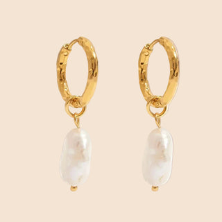 Gold hoop earrings with pearl drops on a white background