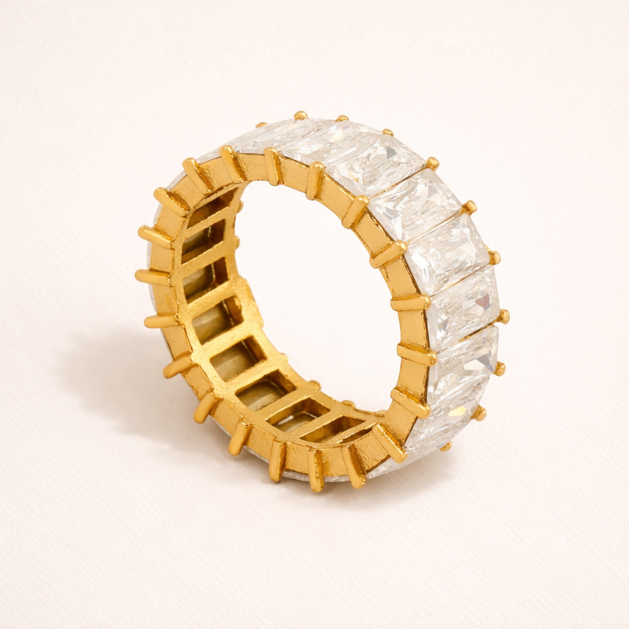 Gold ring with clear gemstones on a light pink background