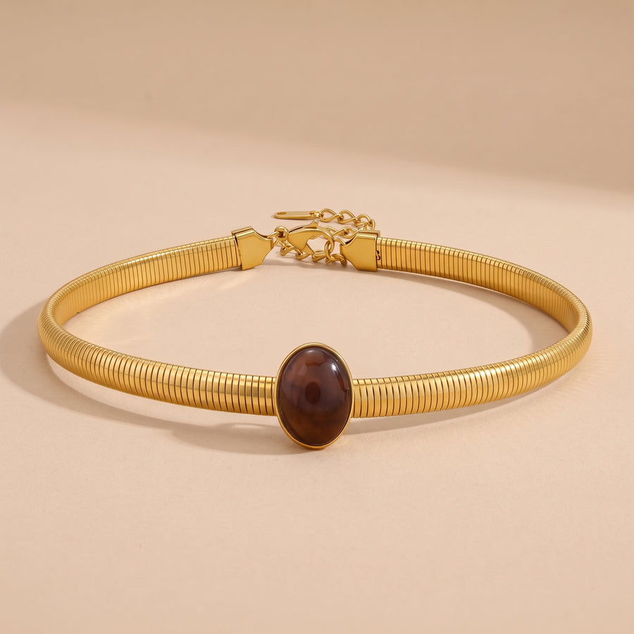 Amber Resin Choker in 18K gold with an oval amber cabochon, on a beige background