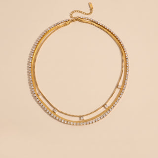 Layered Trio necklace in 18K gold, product shot on a beige background