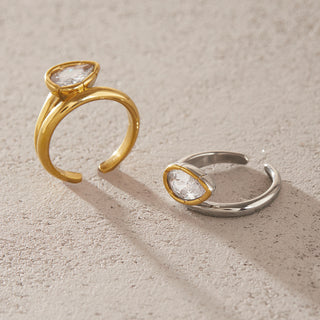 Bezel Elongated Ring in gold and silver tones shown side by side on a beige background