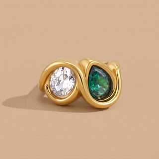 Bezel Emerald Ring in 18K gold with bezel-set clear and emerald zircon stones, close-up on a beige background