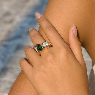 Bezel Emerald Ring worn on a hand outdoors, showing the gold band and dual gemstones