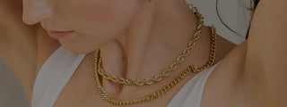 Close-up of a person wearing two gold necklaces