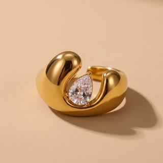 Open Dome Ring in 18K gold with a bezel-set pear-cut zircon, close-up on a warm neutral background
