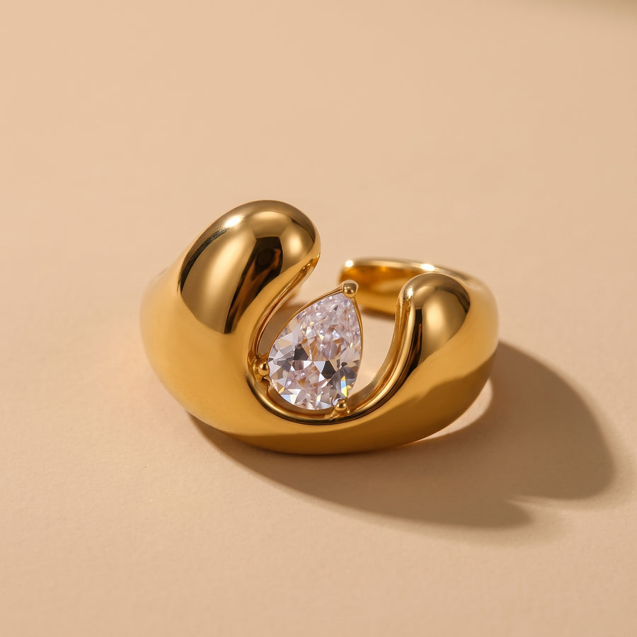 Open Dome Ring in 18K gold with a bezel-set pear-cut zircon, close-up on a warm neutral background