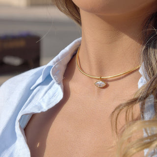 Close-up of a person wearing a gold necklace with a diamond pendant.