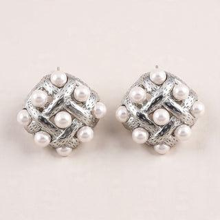 Pair of silver earrings with pearl-like beads on a light background
