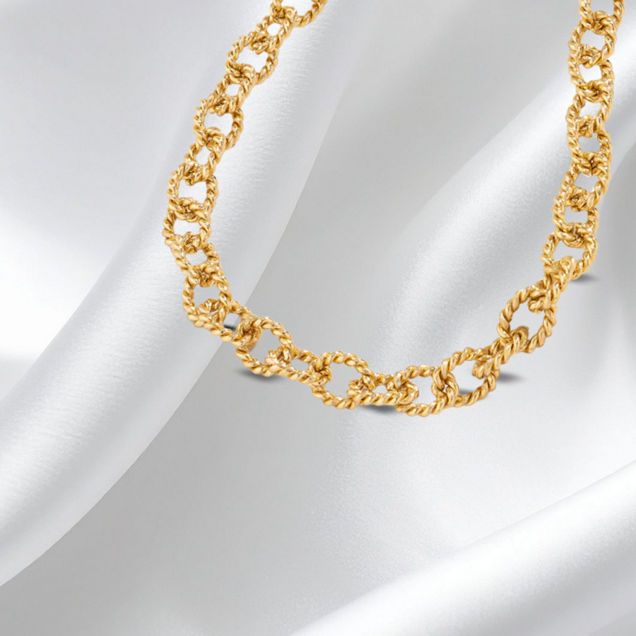 Gold chain necklace on a white fabric background