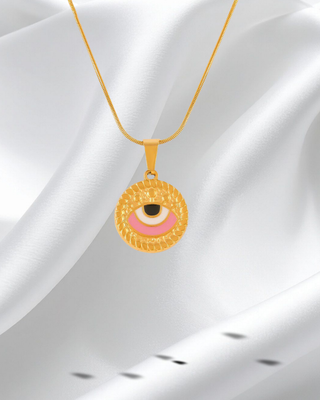 Gold necklace with a round pendant featuring an eye design on a white fabric background