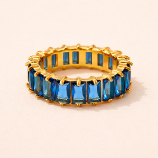 Gold ring with blue gemstones on a beige background
