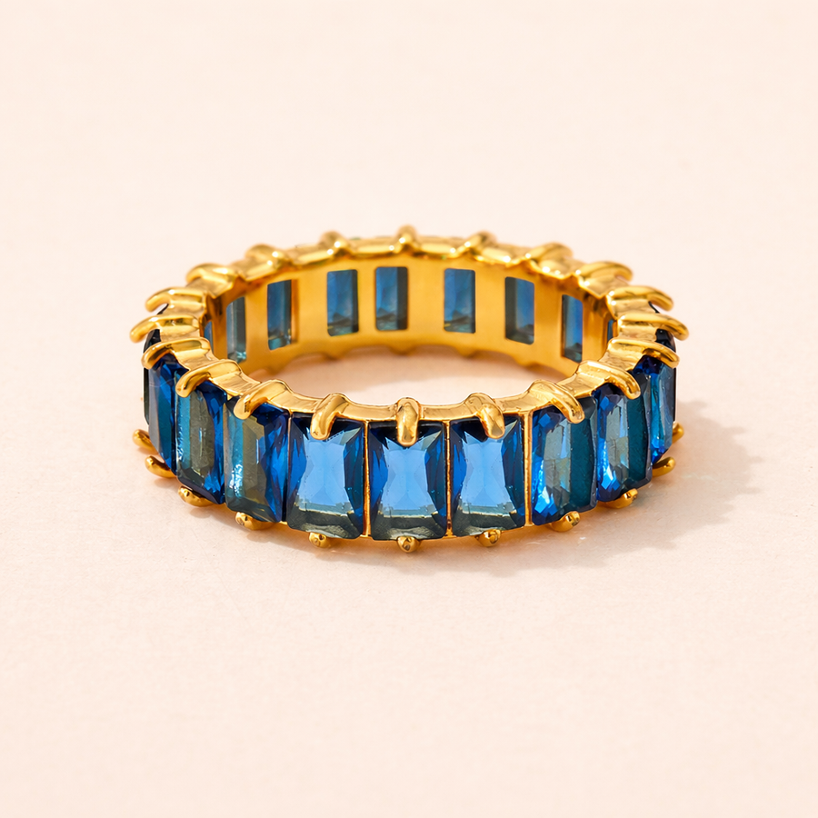 Gold ring with blue gemstones on a beige background