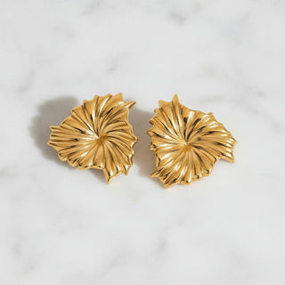 Pair of gold leaf-shaped earrings on a white background