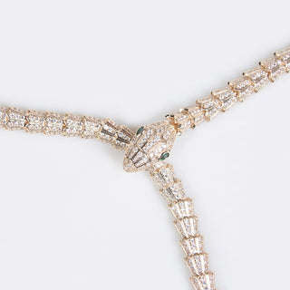 A golden serpent necklace with inlaid diamonds creating a sleek silhouette, displayed against a white background.