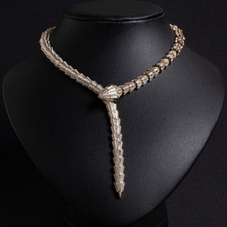 A golden serpent necklace with inlaid diamonds creating a sleek silhouette, displayed against a white background.