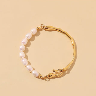 Gold bracelet with pearl beads on a beige background
