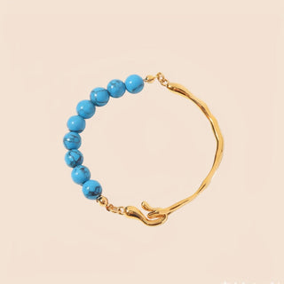 Gold bracelet with blue beads on a beige background