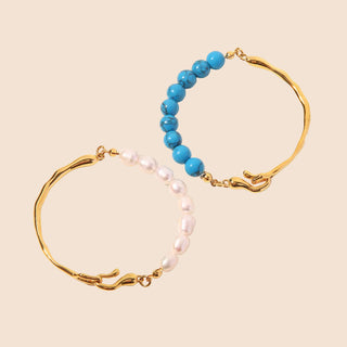 Two gold bracelets with blue and pearl beads on a white background