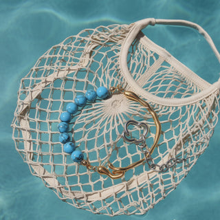 Net bag with blue beads and gold hook on a blue water background