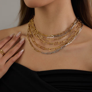 Close-up of a person wearing multiple gold and silver chain necklaces.