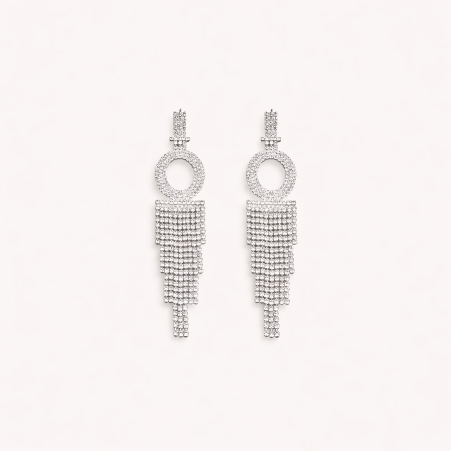 Pair of silver earrings with circular top and tassel design on a light gray background