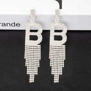 smoddo tassel earrings Silver 'B' letter earrings on a black background with a brand name visible.